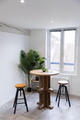 - une table et deux tabourets dans une pièce avec fenêtre dans l'établissement Doux Cocon Tropical au cœur du centre ville, à Troyes