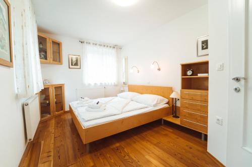 a bedroom with a bed with white sheets and wooden floors at House Planica in Kranjska Gora