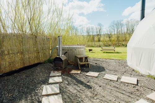 a backyard with a grill and a bench and a fence at Beavers Retreat Glamping in Tenby