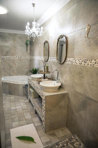 a bathroom with a sink and a tub and a mirror at Big 5 Guest House Witbank in Witbank