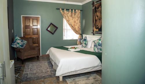 a bedroom with a bed and a chair and a window at Big 5 Guest House Witbank in Witbank