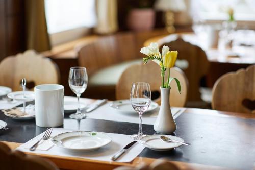 a table with plates and glasses and a vase with flowers at Hotel & Spezialitätenrestaurant zur Linde in Teufen