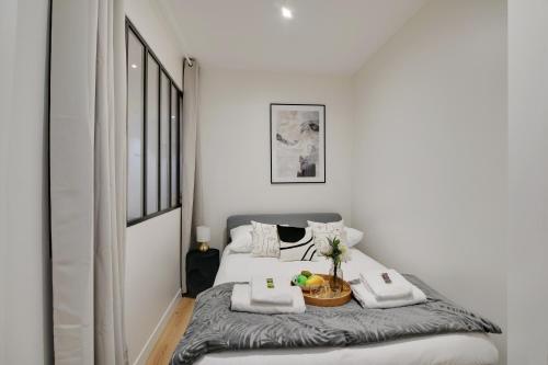 a white bedroom with a bed with towels on it at CMG - Superbe appartement 3BR/8P - Nation/Bercy in Paris