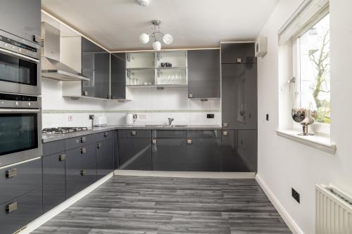 a kitchen with gray cabinets and a window at Executive Apartment, Free Parking, West End in Aberdeen