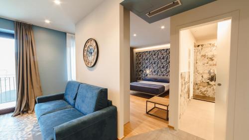 a living room with a blue couch and a bed at Vietti Apartments in Castiglione Falletto