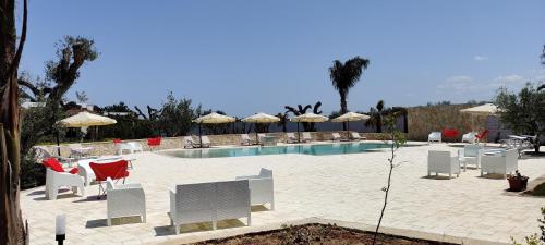 una piscina con sillas, mesas y sombrillas en Gli Ulivi Residence, en Leverano
