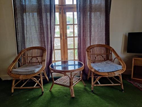 two chairs and a glass table in front of a window at Yountan guest house in Leh
