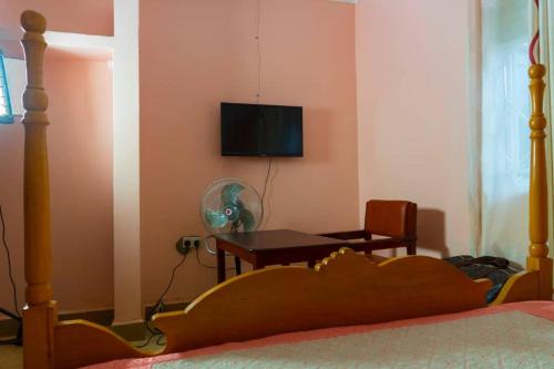 a bedroom with a bed and a table and a television at Gugga Resort in Soroti