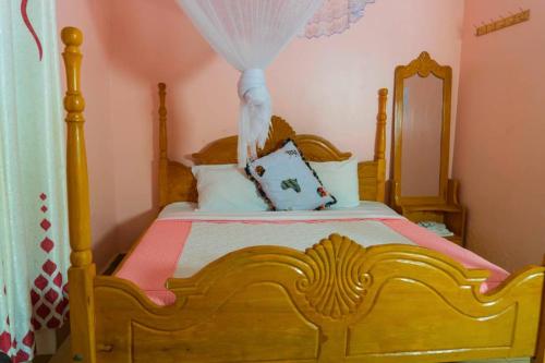 a bedroom with a wooden bed with a canopy at Gugga Resort in Soroti