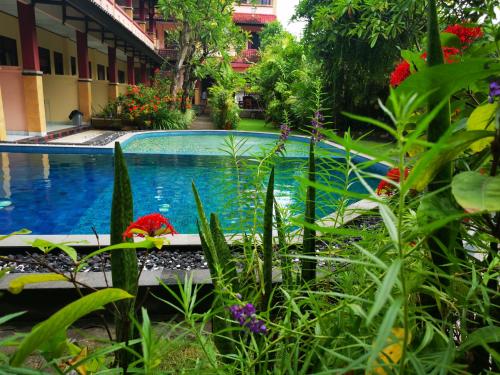 a swimming pool in front of a building with flowers at Celebbest in Kuta