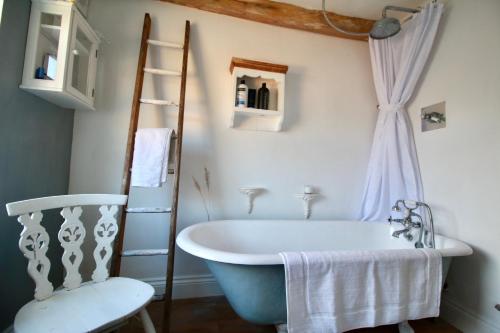 a bathroom with a bath tub and a chair at Cockle Cottage, An artists haven, Charming Cottage By Air Premier in Seaford