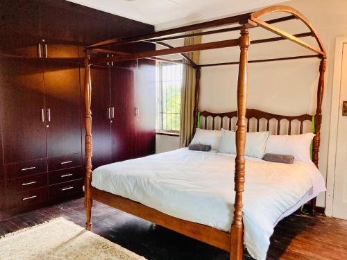 um quarto com uma cama de dossel em madeira com lençóis brancos em Durban Italian villa 1&2 em Durban