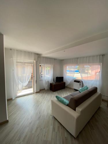 ein weißes Wohnzimmer mit einem Sofa und einem TV in der Unterkunft Appartamento Cannella in Bellagio