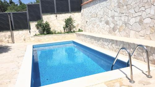 a swimming pool in front of a stone wall at Villa Tina in Ploče