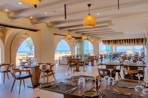 a restaurant with tables and chairs and the ocean in the background at Minos Ambassador Suites & Spa - Adults only in Rethymno Town
