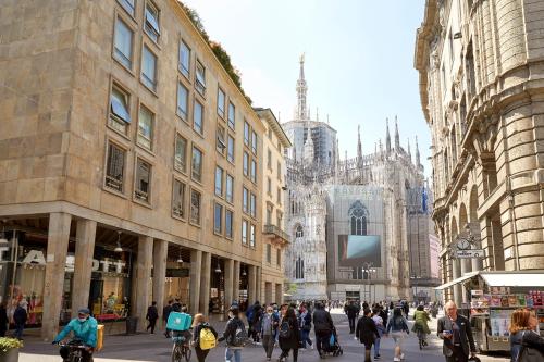 a group of people walking down a street in a city at PRESTIGE BOUTIQUE APARTHOTEL -Piazza Duomo in Milan
