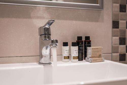 a bathroom sink with a faucet and three bottles of soap at Summer Beach Hotel in Georgioupoli