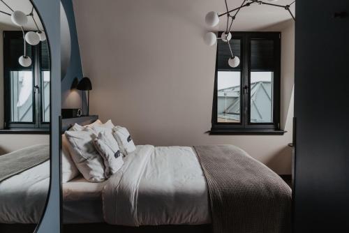 a bedroom with a bed and two windows at The Nox Hotel in Utrecht