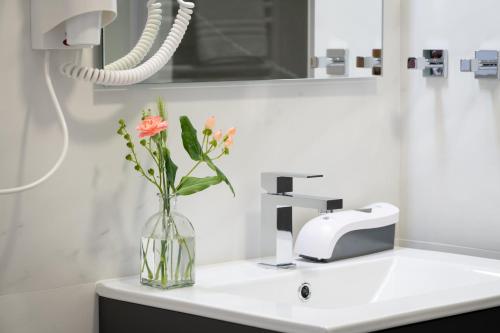 ein Waschbecken mit einer Vase mit Blumen im Bad in der Unterkunft Asturalqui viviendas turísticas adaptadas in Llueves