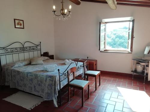 a bedroom with a bed with two chairs and a window at Poggio Massiccioli in Poggibonsi