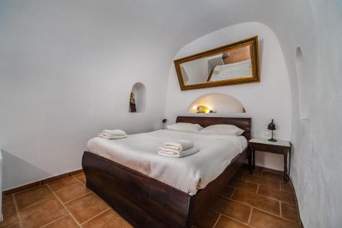 a bedroom with a bed with a mirror on the wall at AURORA VILLA by K&K in Oia