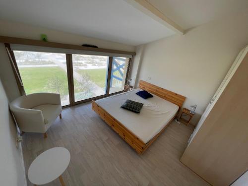 Cette chambre comprend un lit, une chaise et une fenêtre. dans l'établissement L'Oustalet, à Mimizan