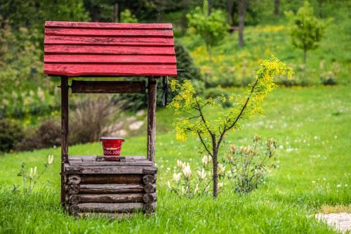a small bird house with a red roof in the grass at Ferrata Vendégház in Csesznek