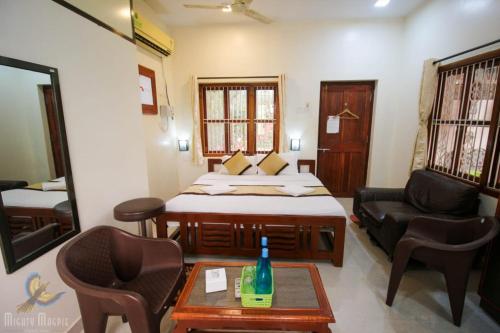 a bedroom with a bed and a couch and a table at Redstone House by Oxystays Hospitality in Ganpatipule