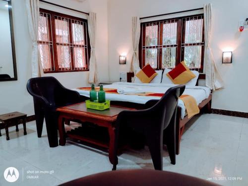 a bedroom with a bed and a table with chairs at Redstone House by Oxystays Hospitality in Ganpatipule