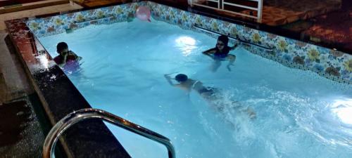 a group of people swimming in a swimming pool at Redstone House by Oxystays Hospitality in Ganpatipule