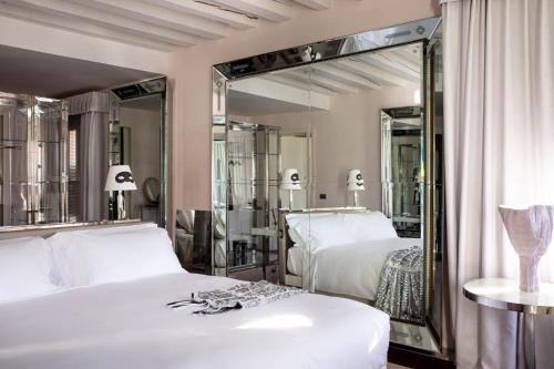 a bedroom with two beds and a large mirror at Hotel Palazzina Grassi in Venice