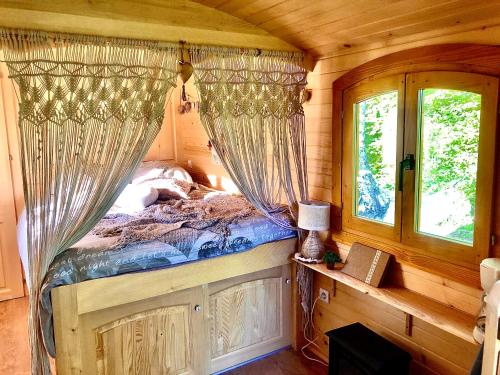 a bedroom with a canopy bed in a log cabin at Roulotte La Chouette des Granges in Les Salles-Lavauguyon