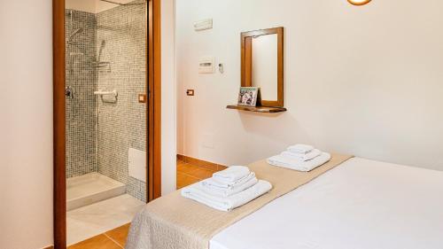 a bedroom with a shower and a bed with towels at Welcomely - Guesthouse Kadossene Alghero in Alghero