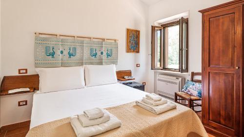 Welcomely - Guesthouse Kadossene Alghero في ألغيرو: غرفة نوم بسرير ابيض كبير عليها مناشف