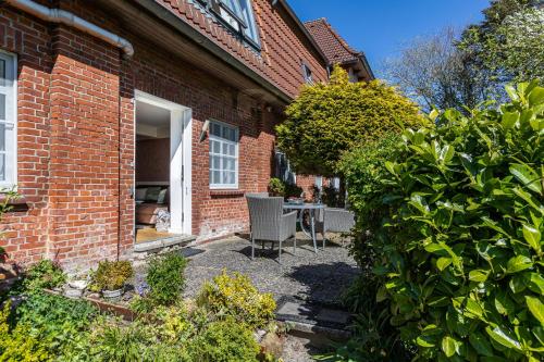 a brick house with a patio in front of it at Denkerhof Fewo Blume des Lebens in Reußenköge