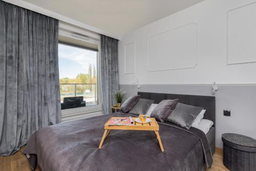 a bedroom with a large bed with a table on it at Apartament Przystań Letnica by Renters in Gdańsk