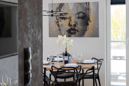 a dining room table with chairs and a painting on the wall at Apartament Przystań Letnica by Renters in Gdańsk