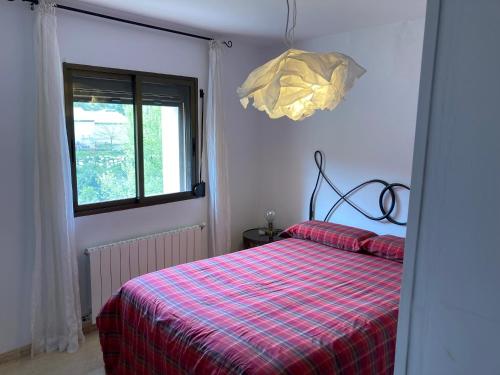 1 dormitorio con 1 cama con manta de cuadros roja en Cal Roig, en Margalef