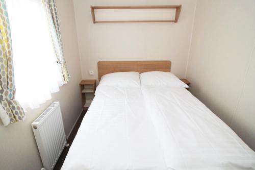a small bedroom with a bed with white sheets at Merlin's Camp in Znojmo