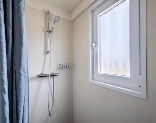 a shower in a bathroom with a window at Strandbungalows Vrouwenpolder in Vrouwenpolder