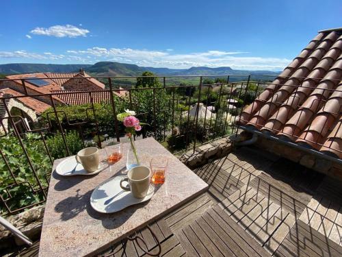a table with two cups and a vase with flowers on it at B&B Maison des Etoiles Chambre d'hôtes Adult Only in Verrières