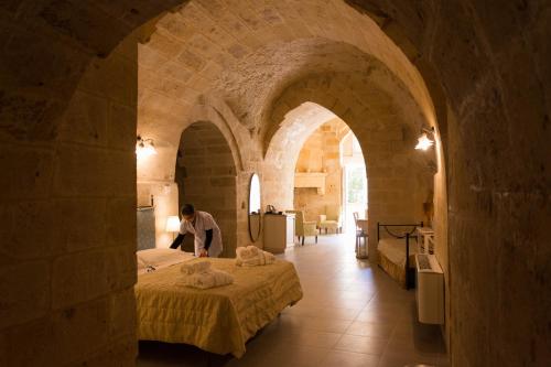 a man sitting on a bed in a stone room at Le Dodici Lune in Matera