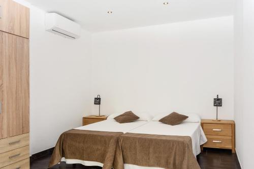 a white bedroom with a bed and two night stands at Apartamentos Mirador in Benidorm