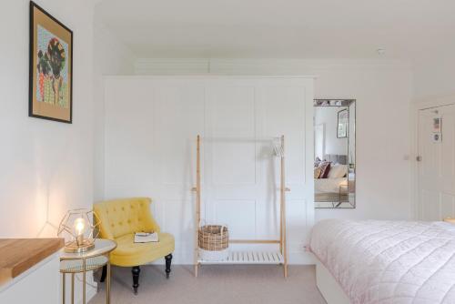 a bedroom with a bed and a yellow chair at 4 Berkeley Square I Your Apartment in Bristol