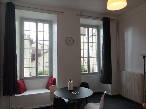 a dining room with a table and two windows at O'Couvent - Appartement 73 m2 - 2 chambres - A311 in Salins-les-Bains