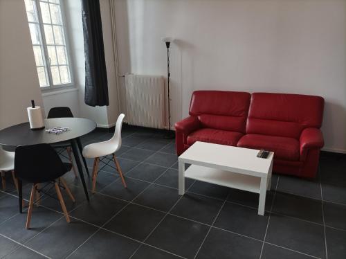a living room with a red couch and a table at O'Couvent - Appartement 73 m2 - 2 chambres - A311 in Salins-les-Bains