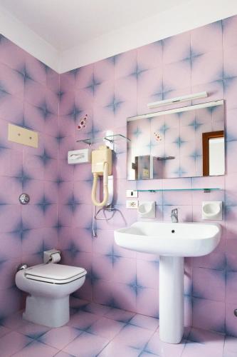 a pink bathroom with a sink and a toilet at Hotel Monaco & Quisisana in Lido di Jesolo