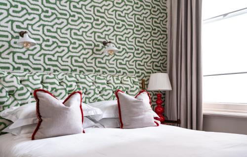 - un lit avec des oreillers blancs et un mur vert et blanc dans l'établissement The Princess Royal, Nothing Hill, à Londres