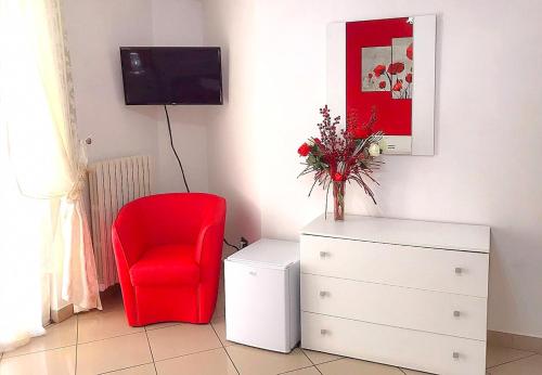 a red chair sitting next to a dresser with a tv at Il Girasole in Vibo Valentia