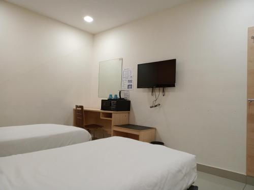 a bedroom with two beds and a tv on the wall at AVENUE BANGI HOTEL in Kajang